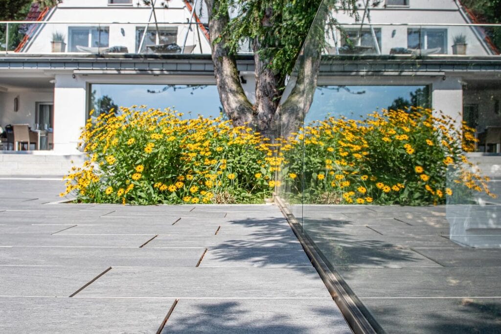 Blühstreifen mit gelben Blumen vor einer Gebäudedurchfahrt