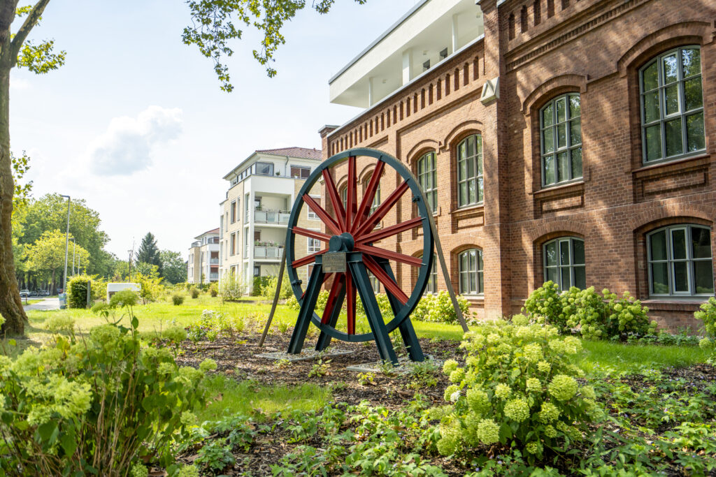 Grünanlage mit historischem Förderrad vor Backsteingebäude in Lünen